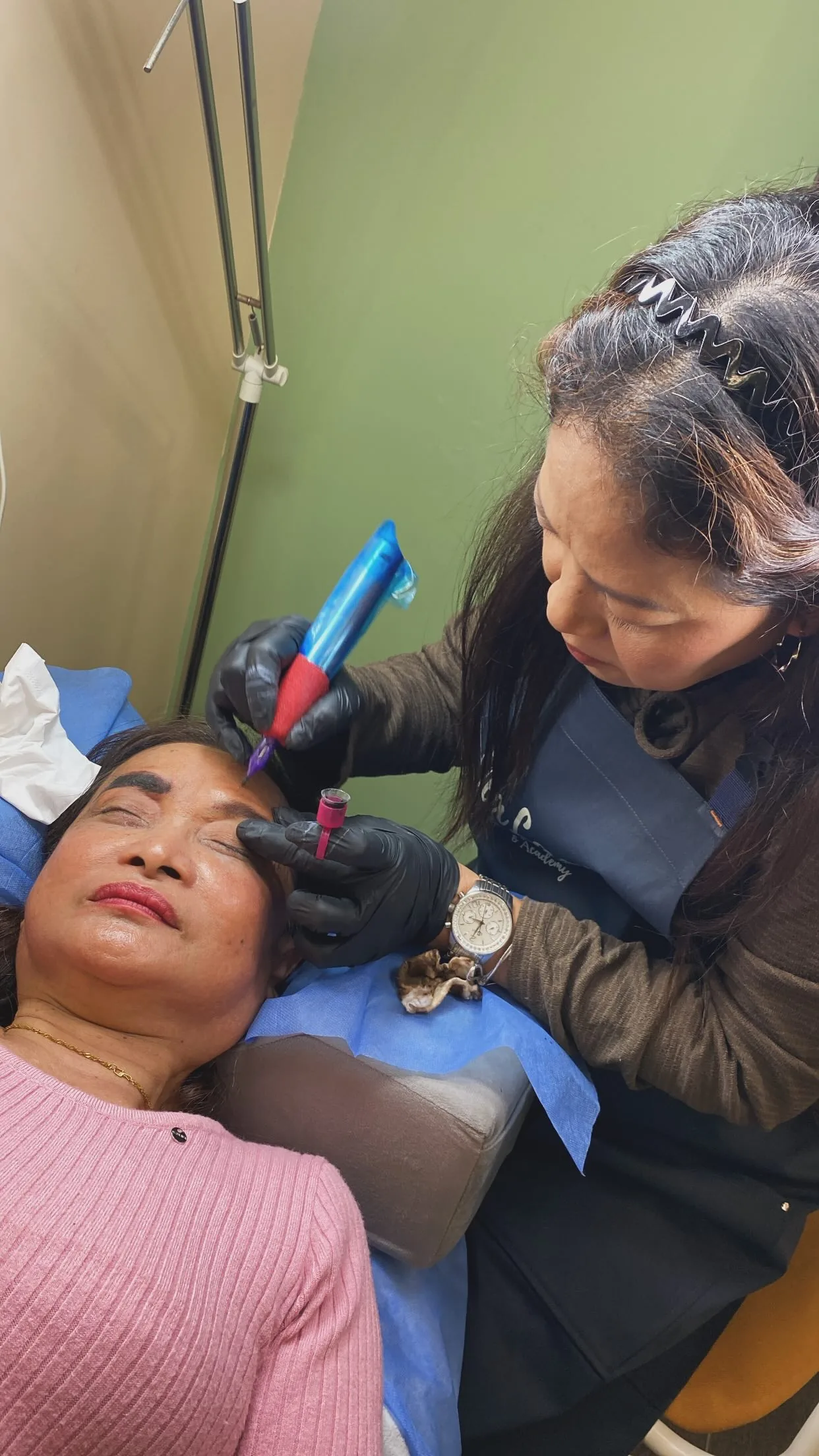 Student using a PMU machine on a live model during Jealash brow training