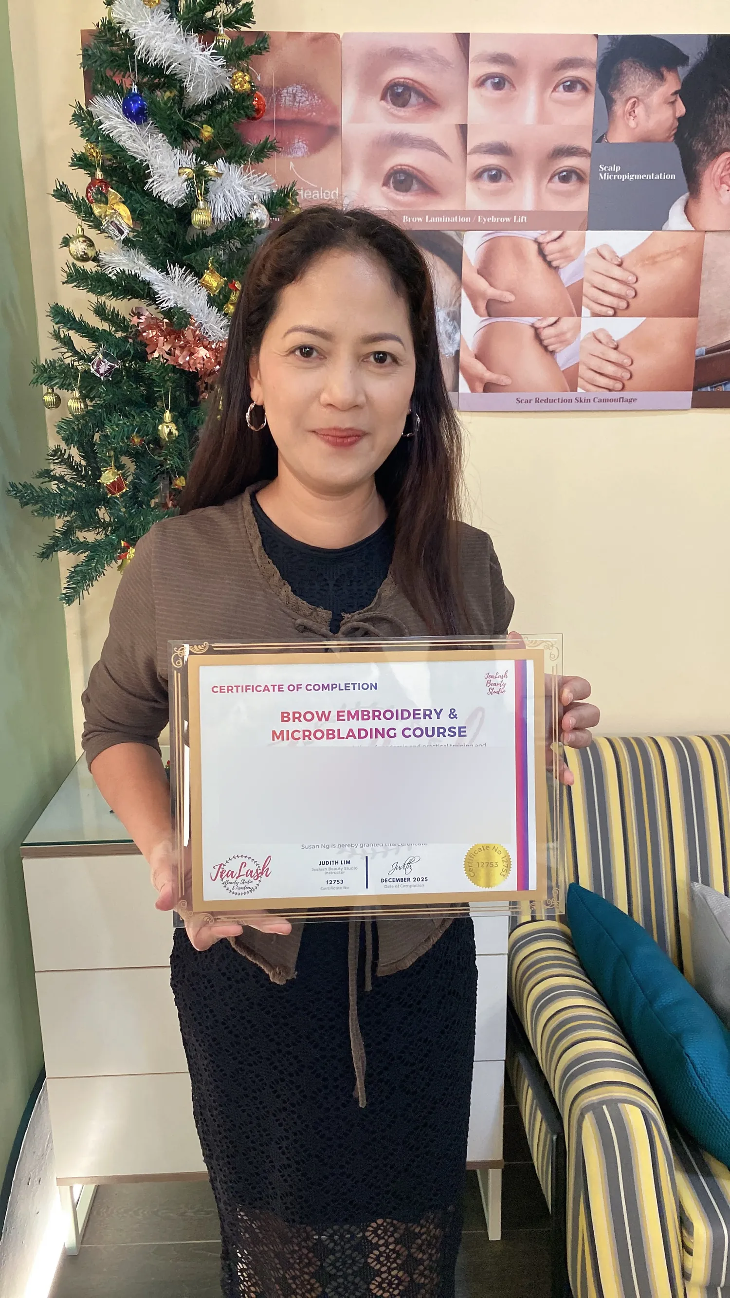 Jealash Brow Embroidery and Microblading graduate holding her certificate with the student name obscured for privacy