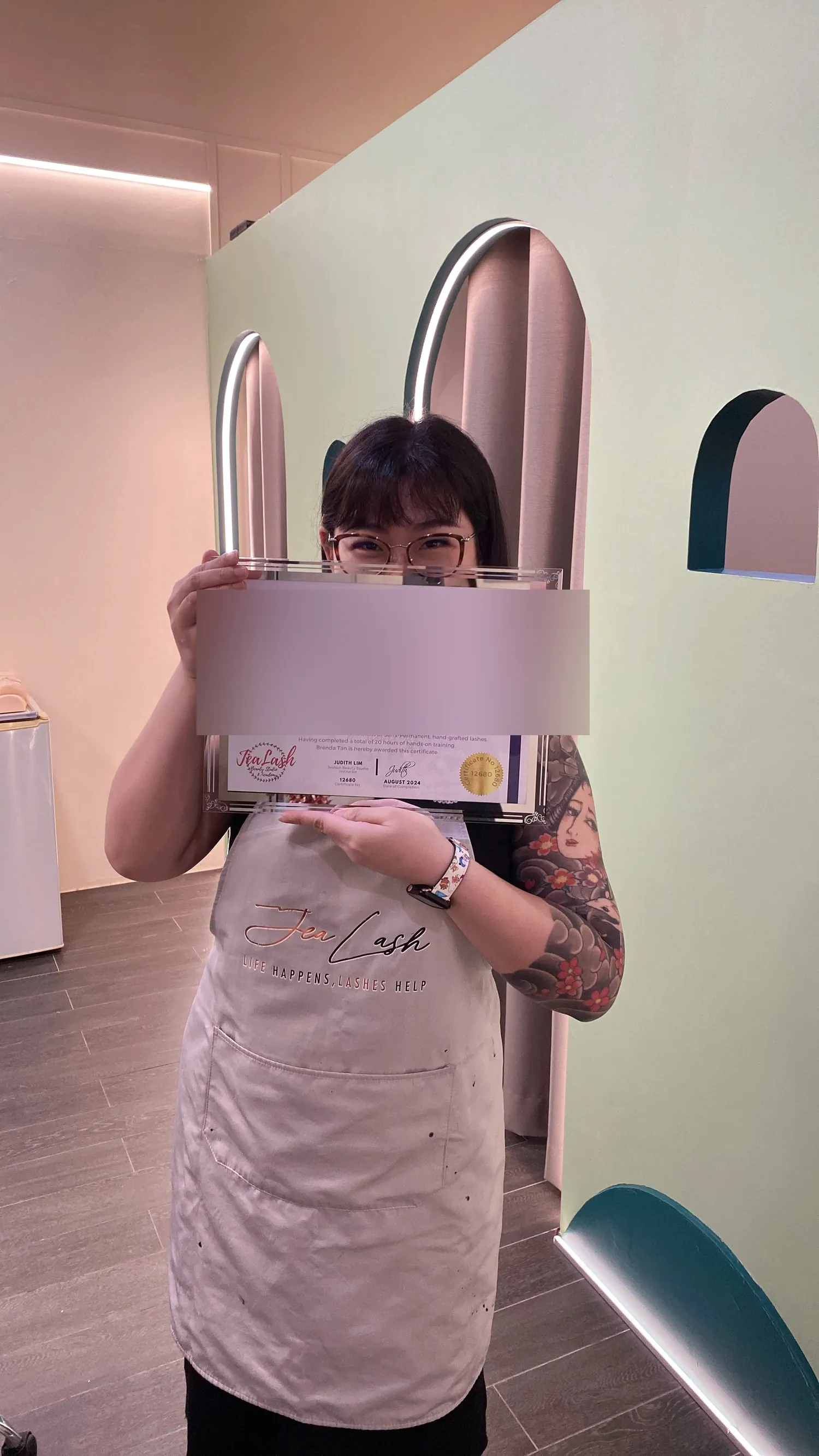 Jealash graduate holding a Basic and Advanced Eyelash Masterclass certificate with the student name blurred for privacy