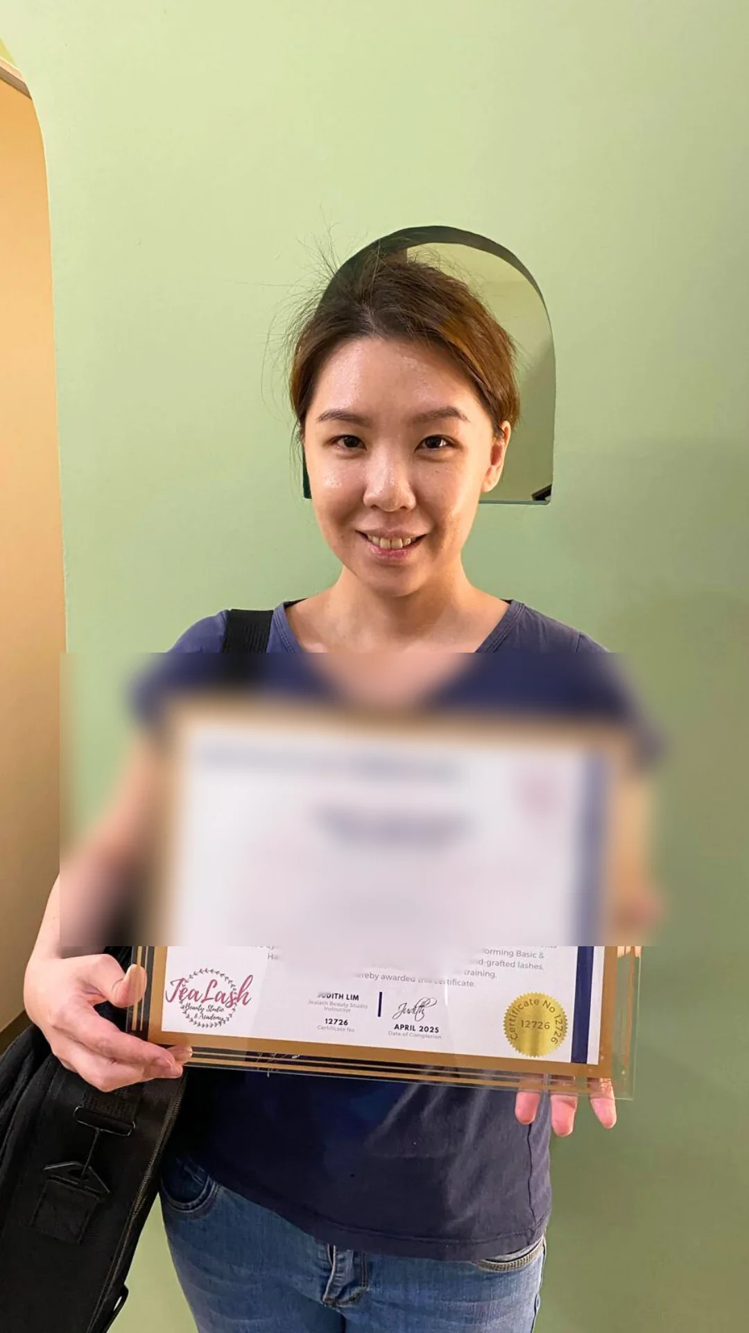 Jealash graduate holding a privacy-blurred course completion certificate